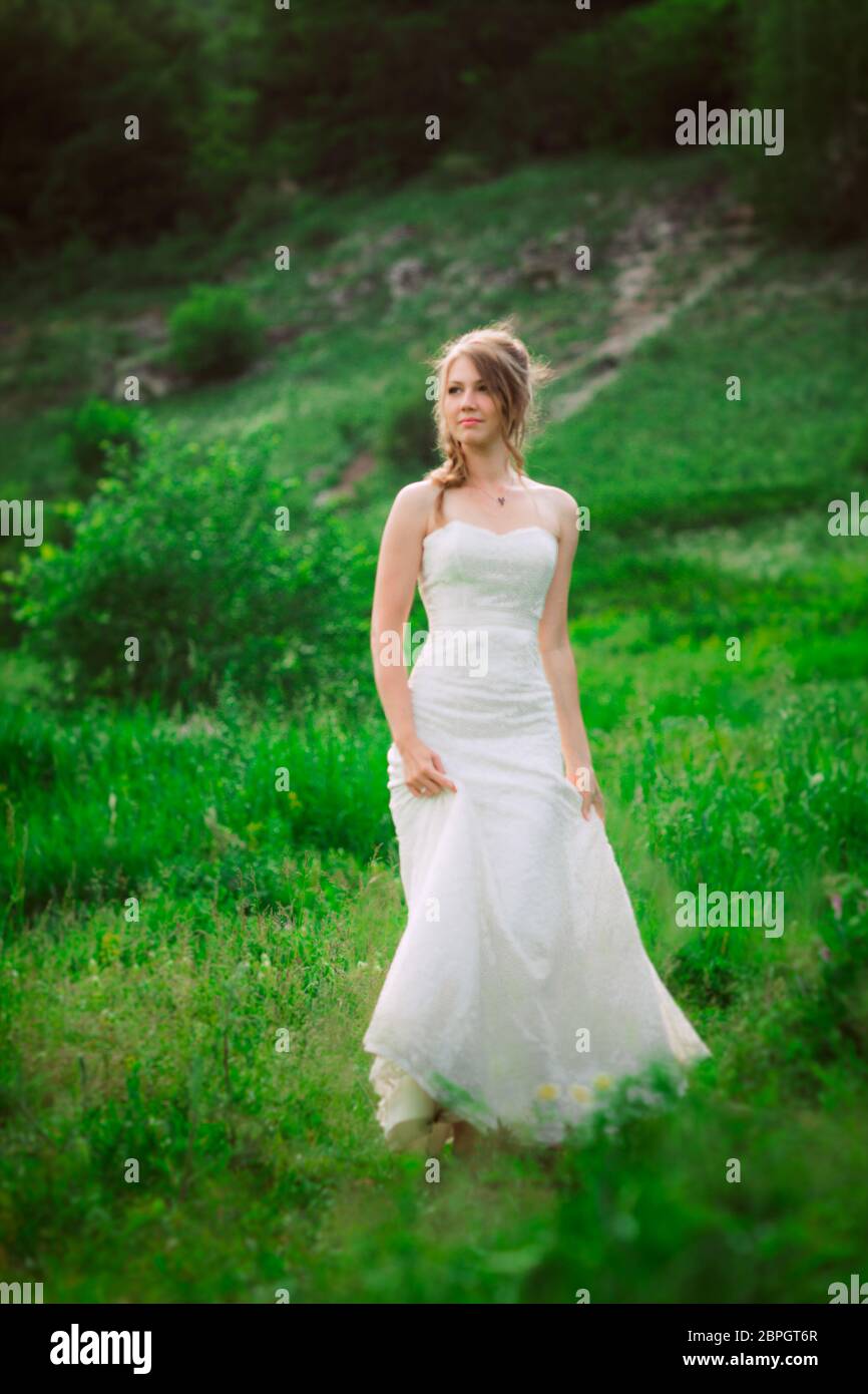 Bella Sposa contro lo sfondo della montagna e dell'erba. Foto Stock