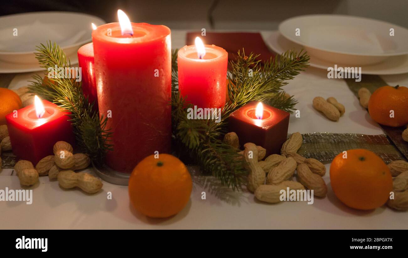 Le decorazioni di Natale su un tavolo. Candele rosse con mandarin e arachide. Foto Stock