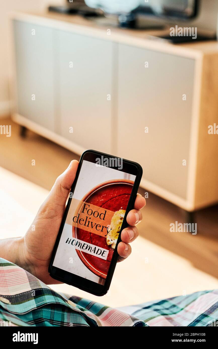 primo piano di un giovane caucasico, vestendo abiti casual, seduto comodamente in una poltrona interna, con lo smartphone in mano con il testo Foto Stock