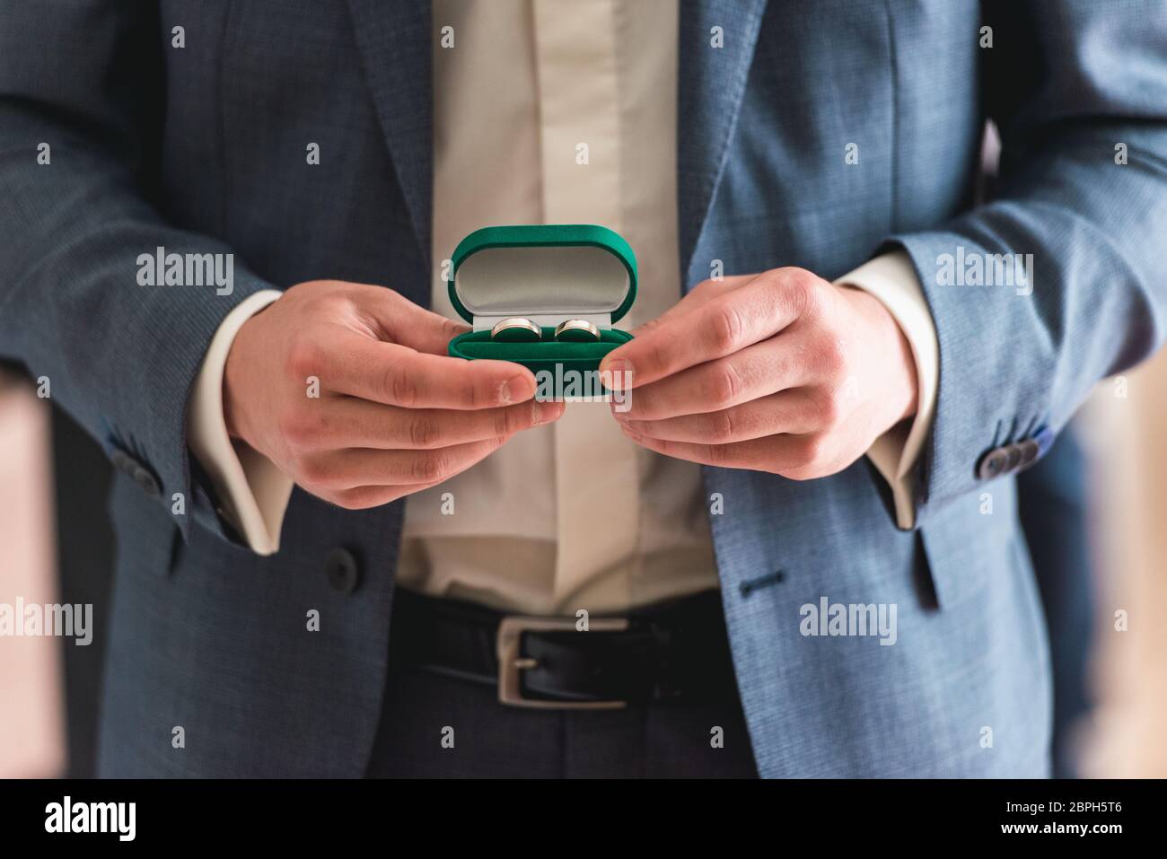 anelli di nozze d'oro in una scatola verde nelle mani di una fianza Foto Stock