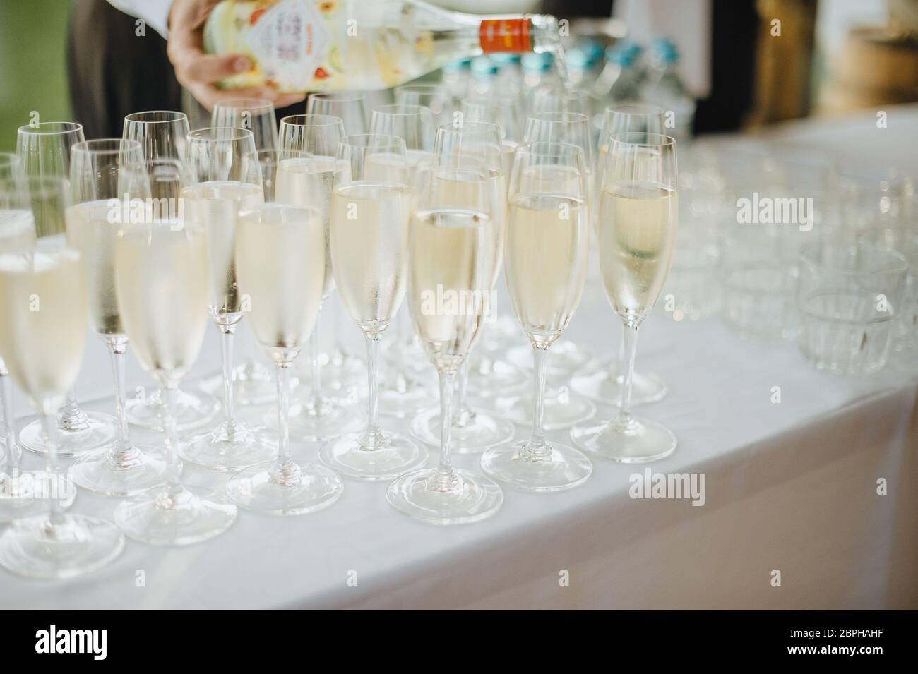 Molti bicchieri con champagne sono sul tavolo. Il tavolo è coperto da una tovaglia bianca Foto Stock