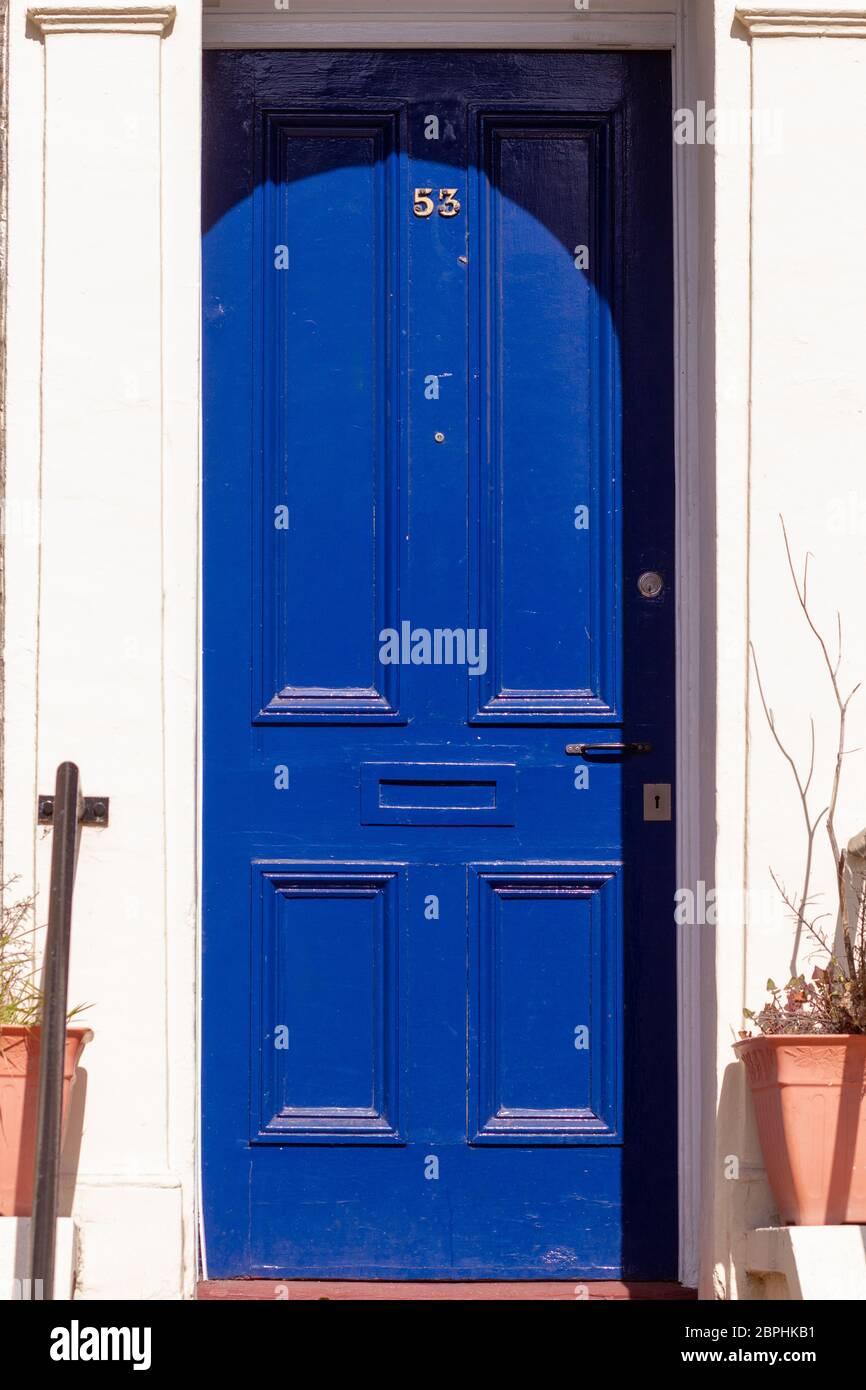 Casa numero 53 su una porta di fronte di legno blu reale con linee verticali a Londra con cornice e facciata bianche Foto Stock