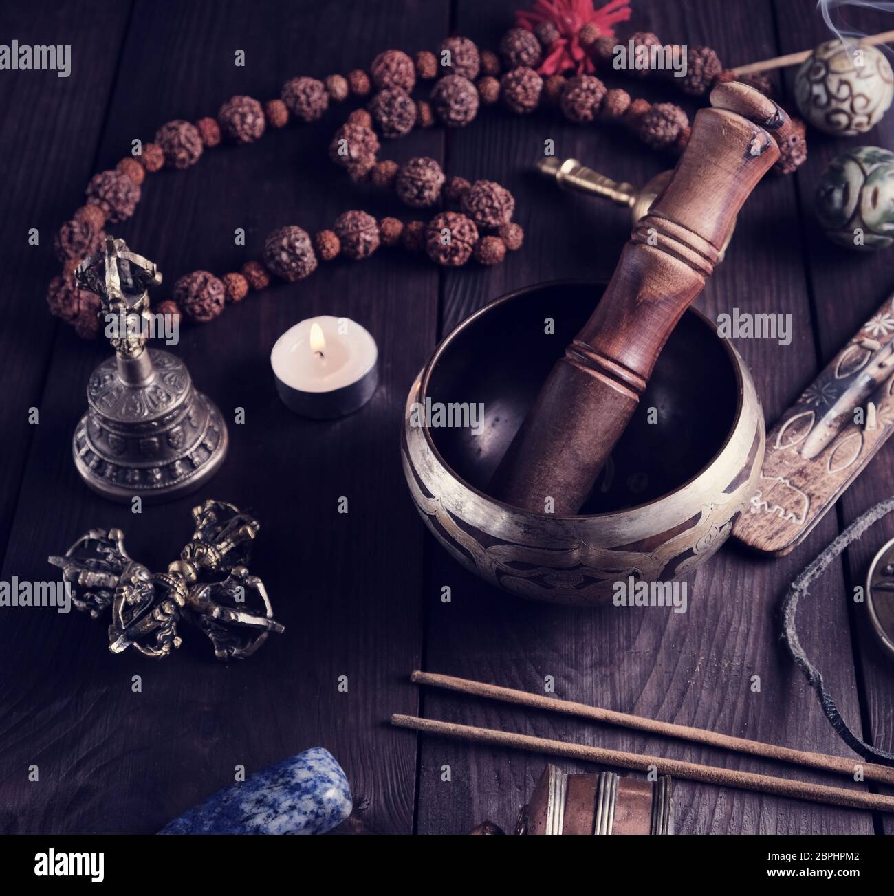 Il rame Singing Bowl, grani di preghiera e altre religiose tibetane oggetti per la meditazione e la medicina alternativa su uno sfondo di legno Foto Stock