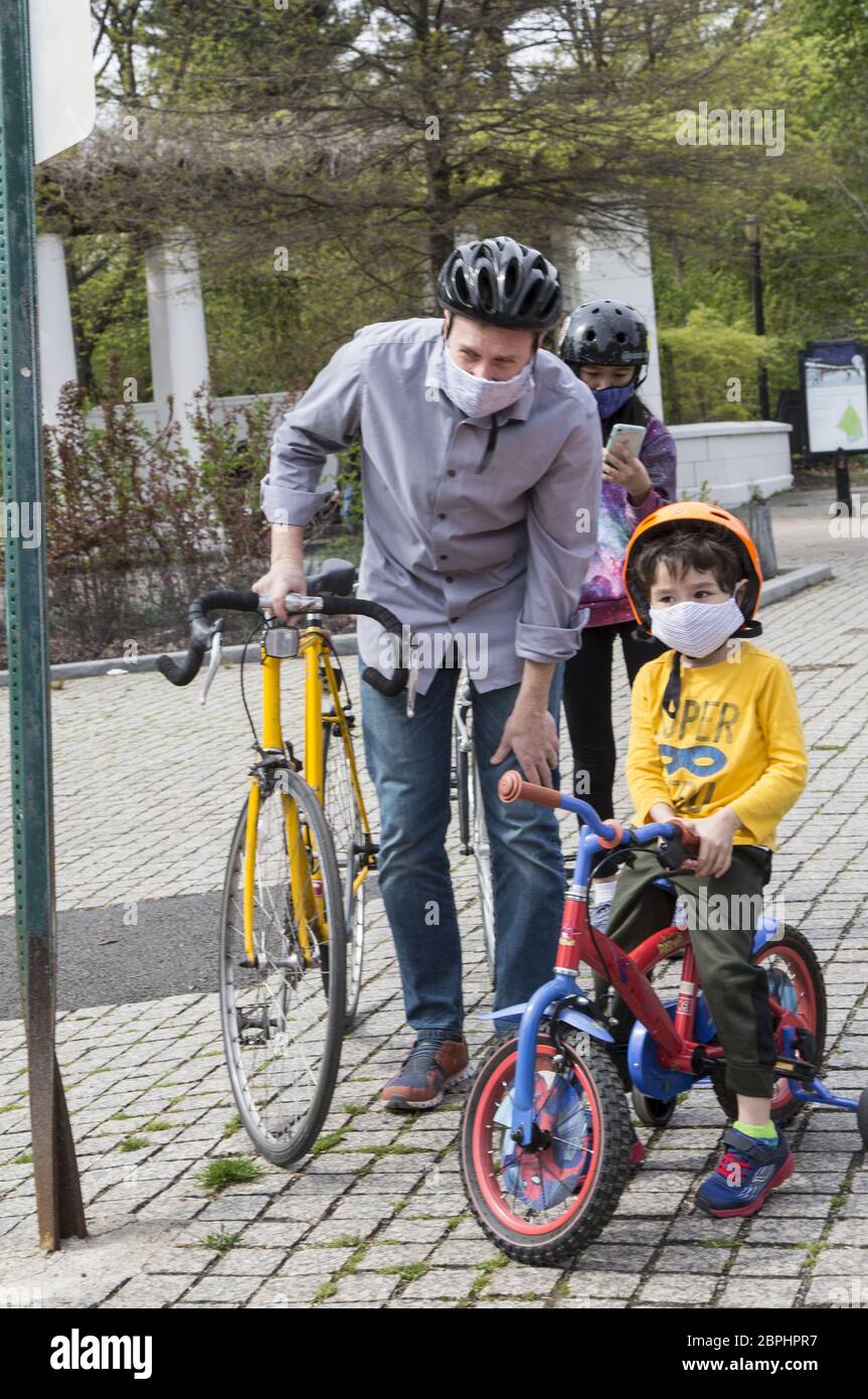 Padre e figlio indossano maschere durante la pandemia di Civid-19 mentre guidano le bici al Prospect Park a Brooklyn, New York. Foto Stock