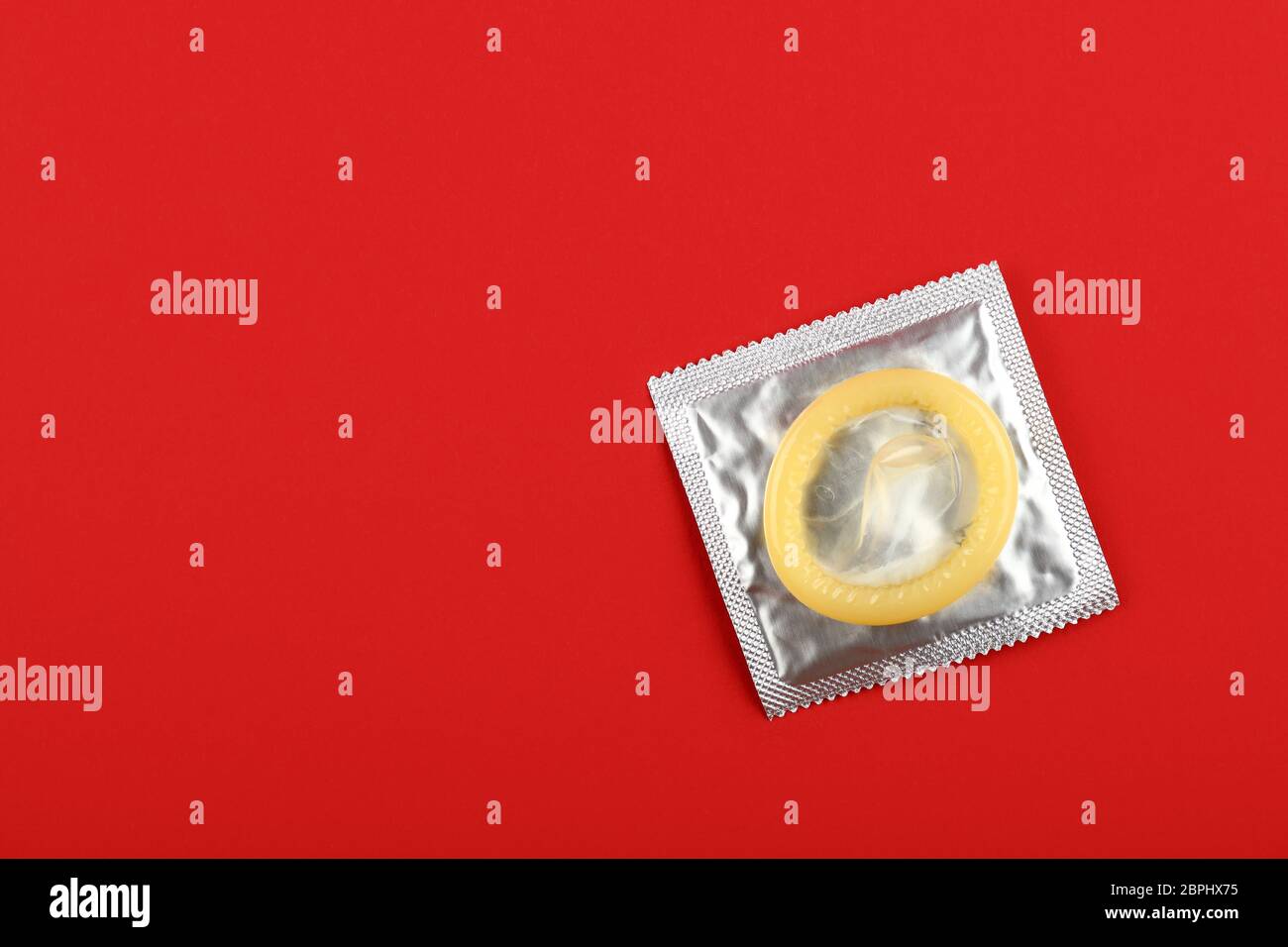 Chiudere un preservativo di lattice su argento wrap pack su vivid sfondo rosso con copia spazio, elevata angolo visuale, direttamente sopra Foto Stock