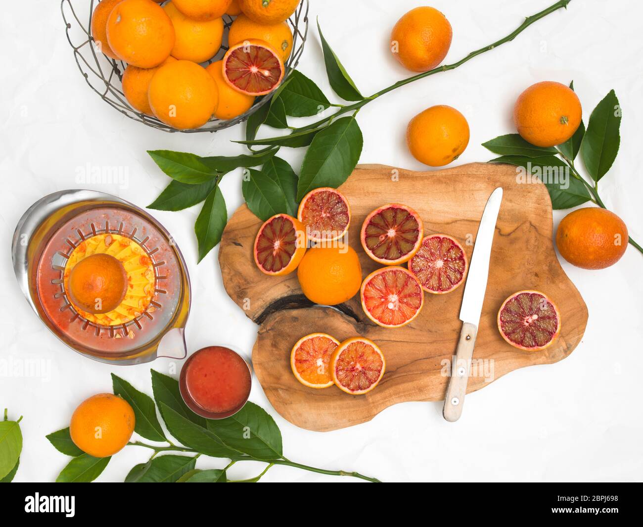 Bella la vita ancora con arance sanguigne sulla carta bianca di sfondo e tavola di legno e il coltello Foto Stock