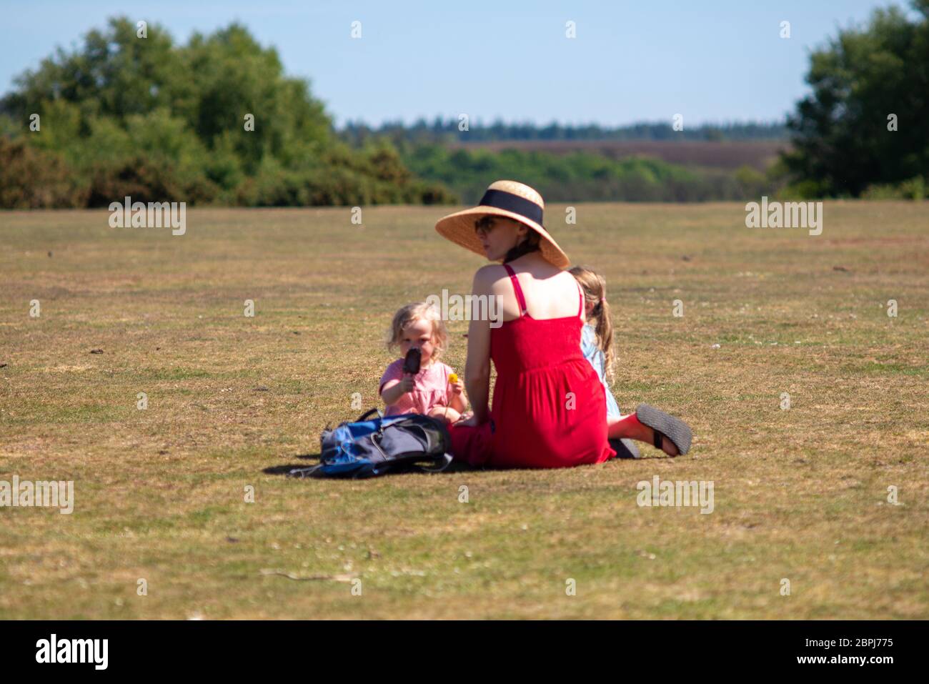 Abbastanza caldo per un cappello e un gelato per una donna e i suoi bambini in primavera, Godshill, New Forest, Hampshire, Regno Unito, 19 maggio 2020, Meteo. Foto Stock