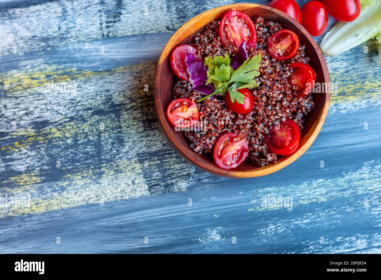 Insalata di quinoa rosse con pomodoro su un tavolo rustico. Concetto di cibo sano e supercibo. Foto Stock