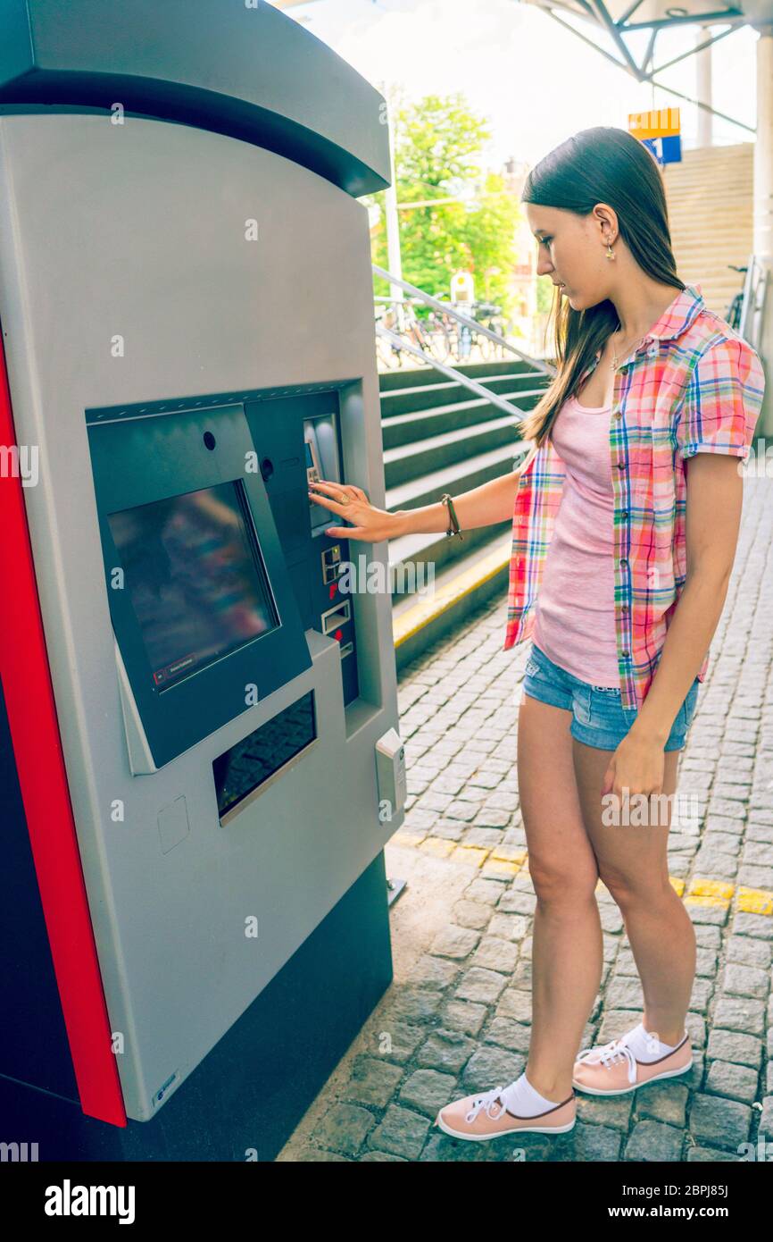 Giovane donna usa un distributore automatico per i biglietti di trasporto Foto Stock