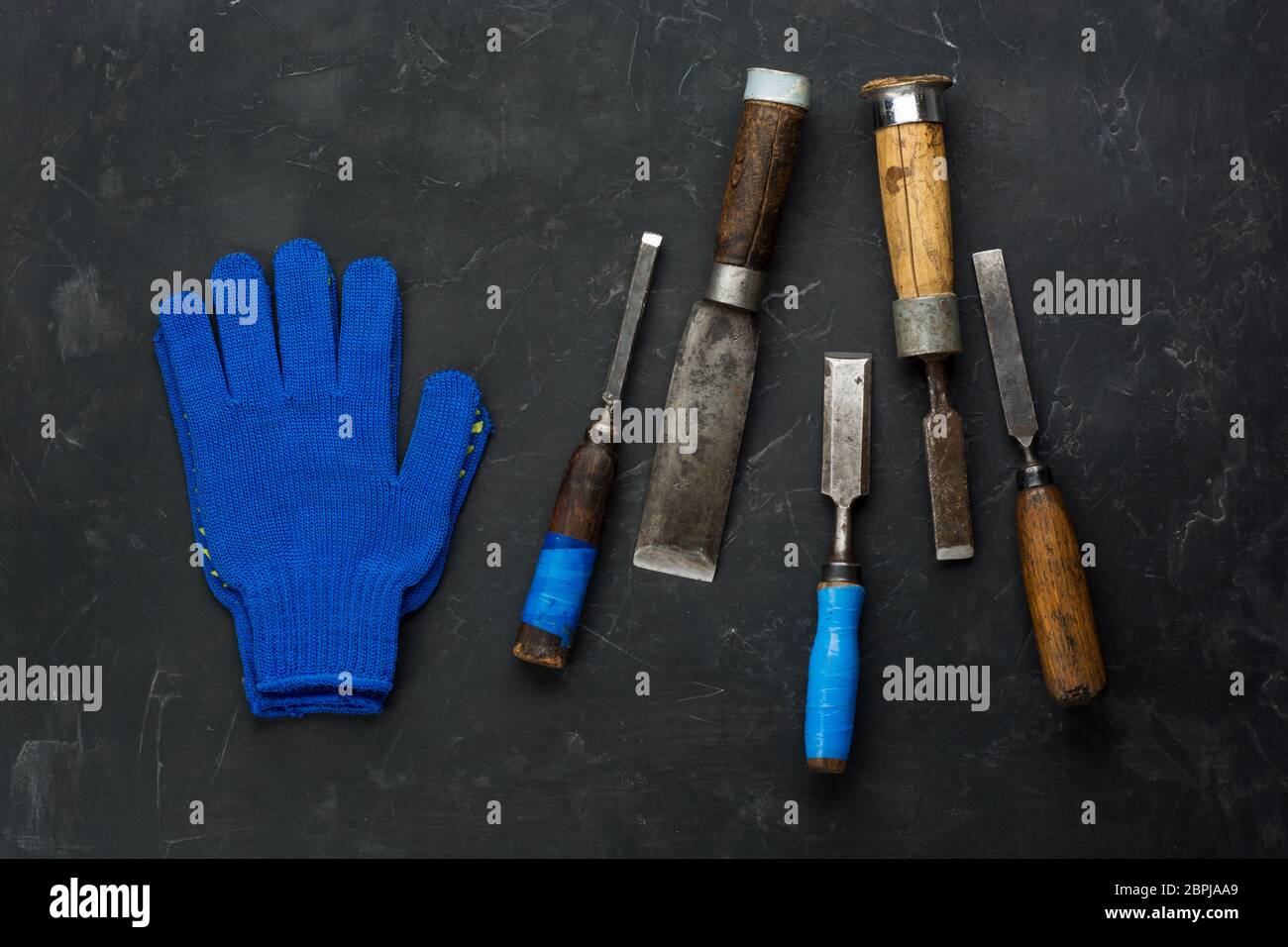 Carpentiere attrezzi e guanti da lavoro su sfondo scuro. Nero minimo. Foto Stock