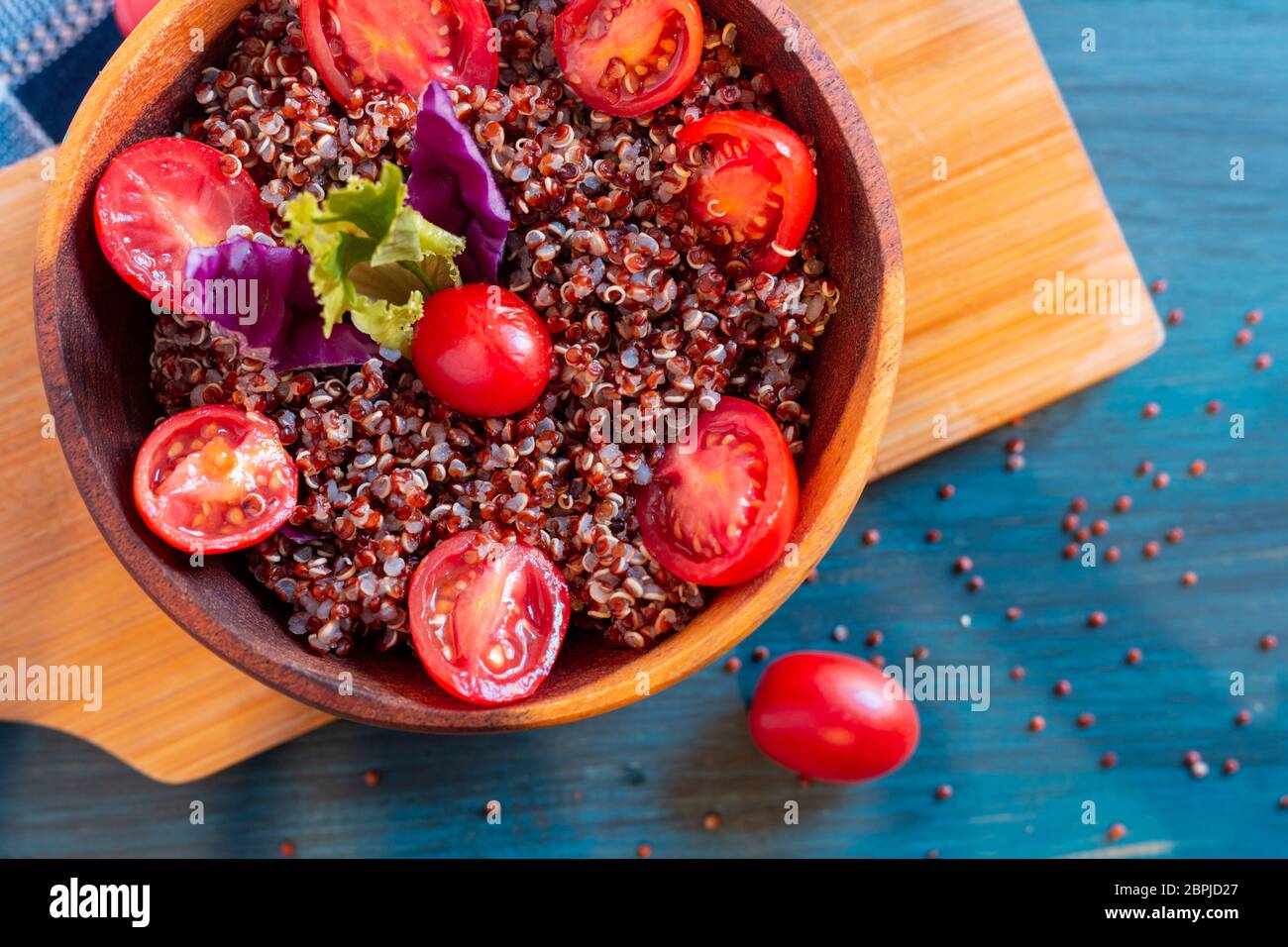 Insalata di quinoa rosse con pomodoro su un tavolo rustico. Concetto di cibo sano e supercibo. Foto Stock