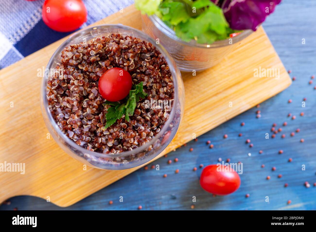 Insalata di quinoa rosse con pomodoro su un tavolo rustico. Concetto di cibo sano e supercibo. Foto Stock