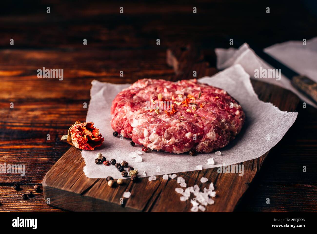 Raw polpetta di carne di manzo con spezie sul tagliere per Burger. Foto Stock