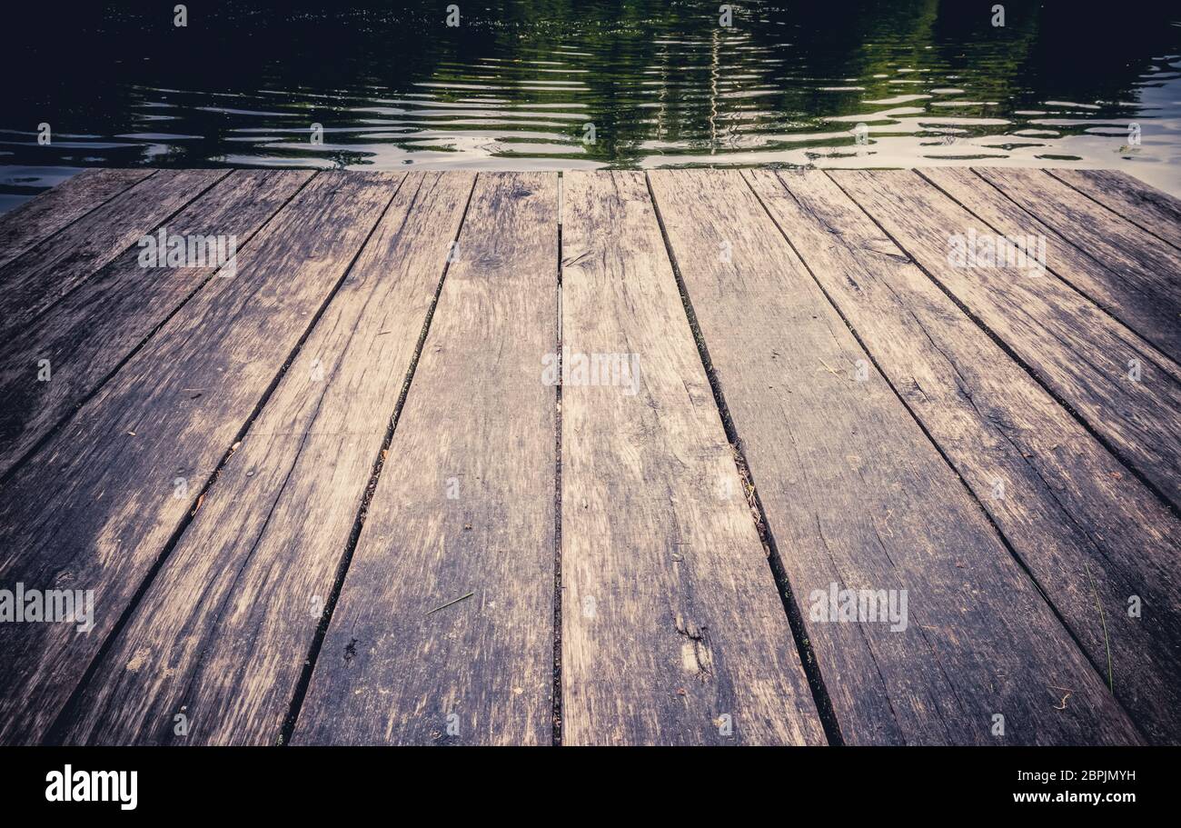 Tavole di legno d'epoca con sfondo lago forestale riposano sul lago forestale Foto Stock
