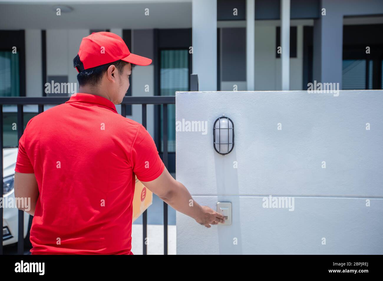 I militari asiatici che indossano una divisa rossa con un cappuccio rosso che maneggia le scatole di cartone da dare al cliente davanti alla casa e fare clic sul do Foto Stock