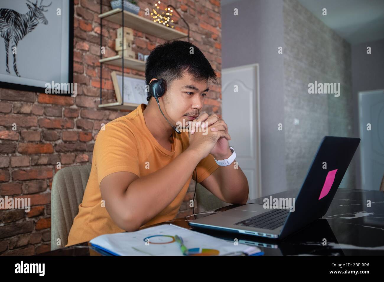 Gli uomini d'affari asiatici utilizzano computer notebook e indossano cuffie per riunioni online e lavorare da casa. Foto Stock
