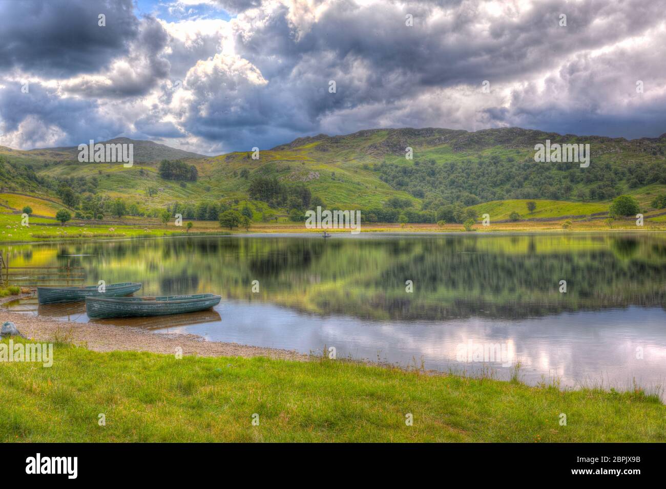 Lago inglese tranquillo con barche a remi Watendlath Tarn i laghi Cumbria Inghilterra HDR Foto Stock