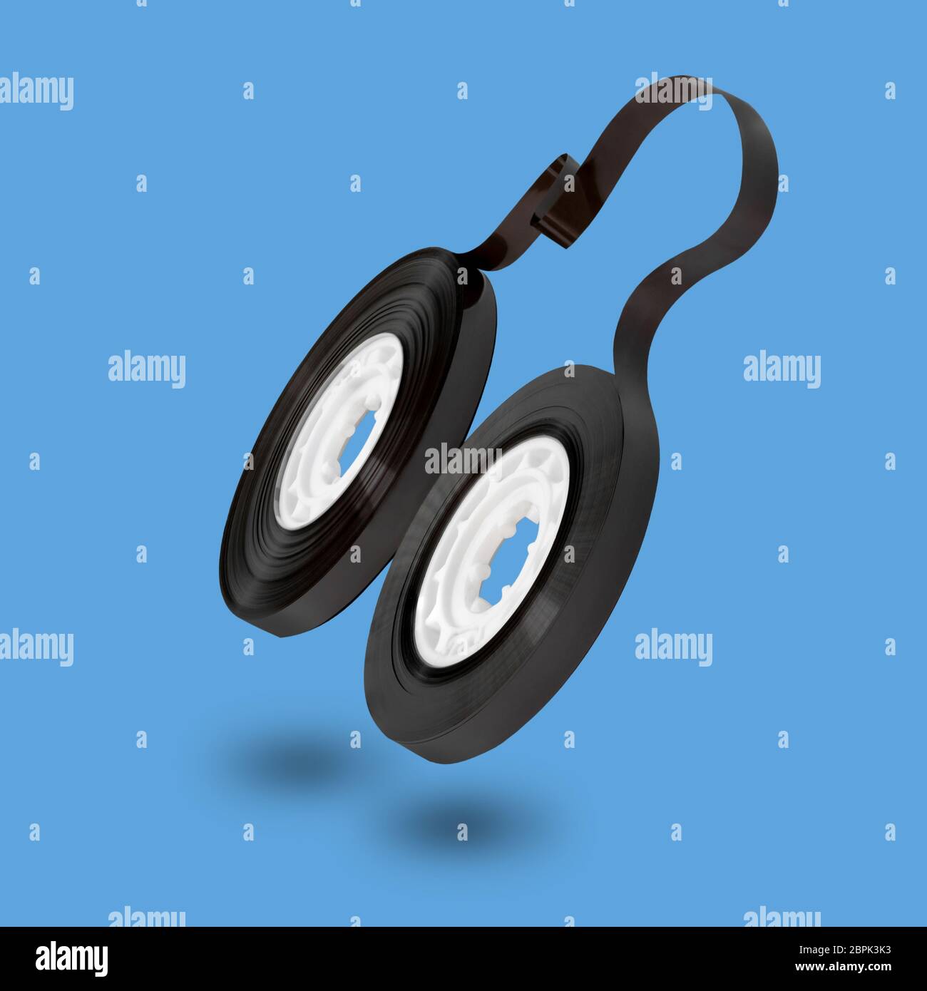Concetto retrò vintage. Nastro musicale senza custodia che si leva in aria e che getta l'ombra su sfondo blu con spazio per la copia Foto Stock