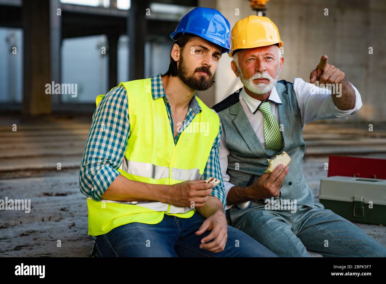 Felice maturo e giovane ingegnere, architetto, lavoratore seduto al sito di costruzione e di appoggio Foto Stock