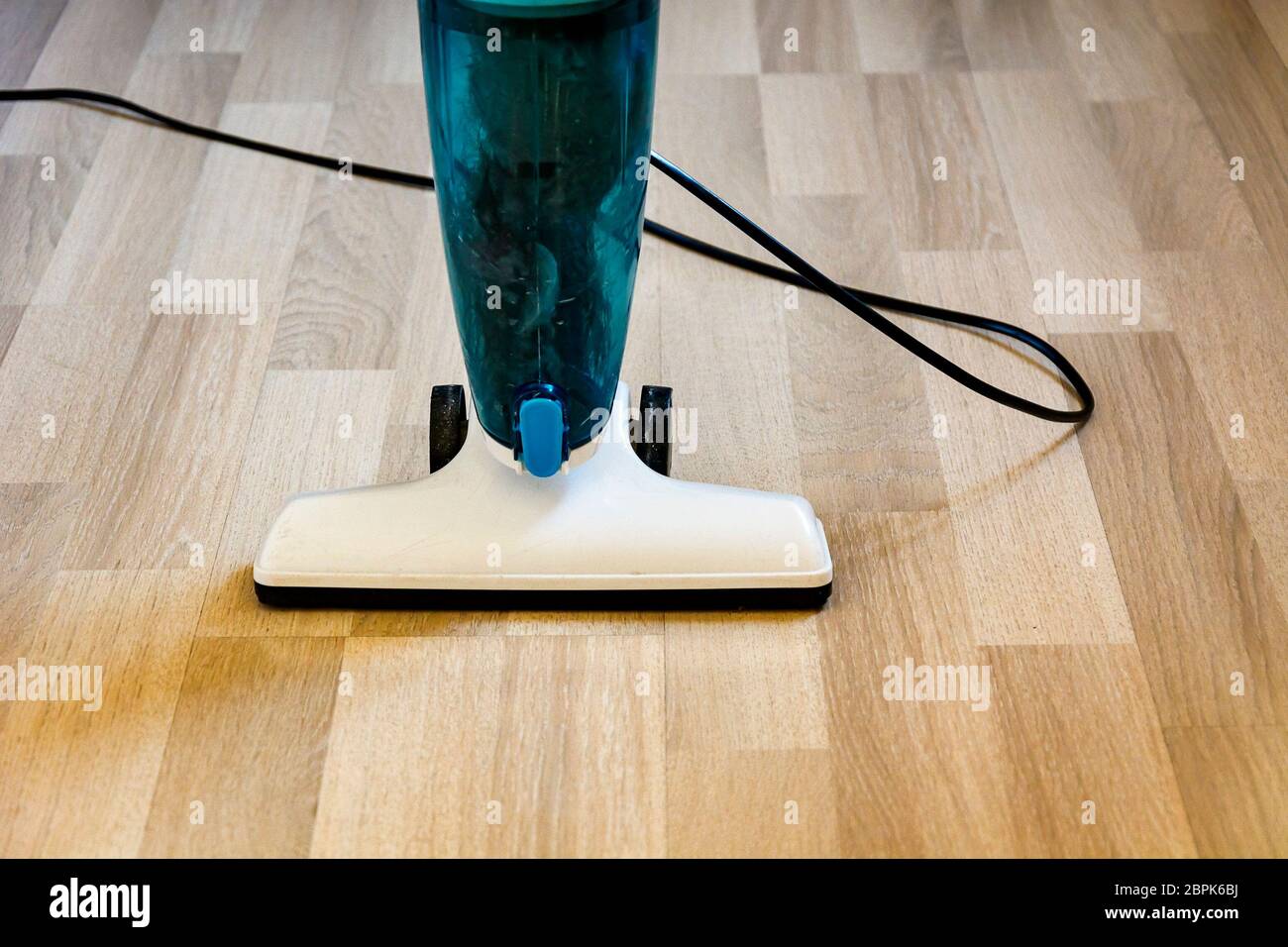 Aspirapolvere su una luce pavimento in parquet. Interior shot. Foto Stock