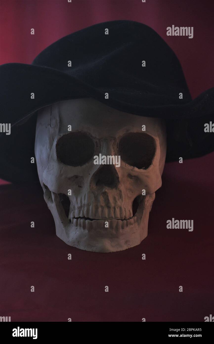 oscuro immagine oscura del cranio umano (replica) in un cappello che è a grande creepy e sciocco Foto Stock