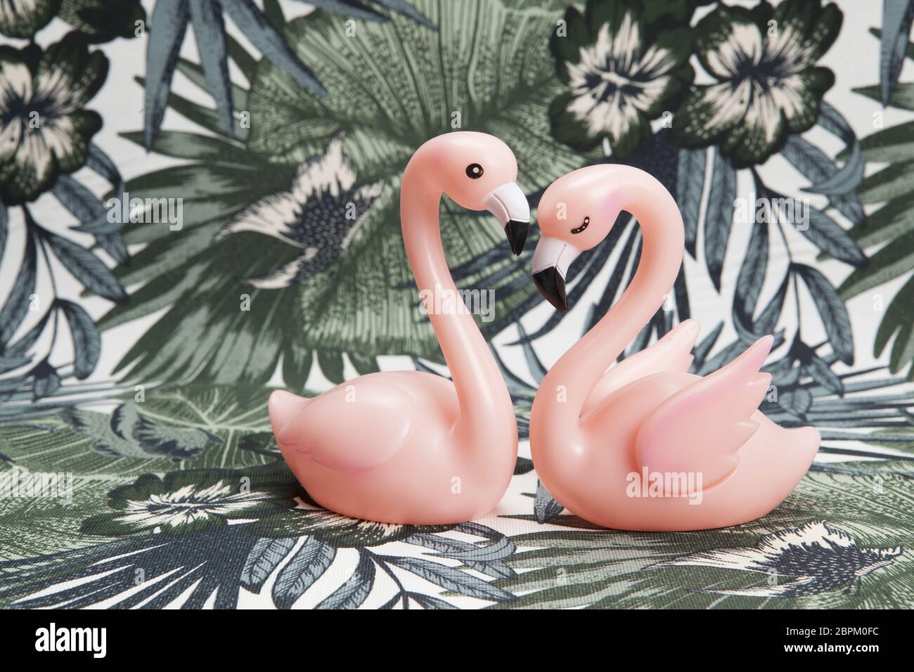 Un paio di plastica rosa fenicottero rosa su uno sfondo tropicale. Il minimo di still life fotografia a colori. Foto Stock