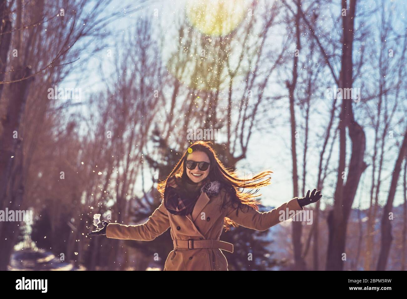 Ritratto di una bella ragazza che indossa gli occhiali da sole e con il piacere di trascorrere del tempo in una luminosa giornata di sole in inverno park, divertirsi come un bambino, felice inverno Foto Stock