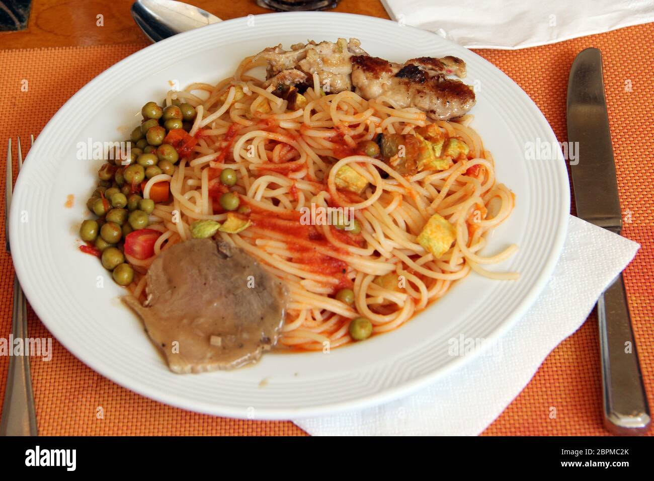 Piatto al ristorante vermicelli salsa di piselli con forchetta e coltello. Spaghetti con verdure di carne e salsa. Pasta cotta con manzo e piselli su piatto Foto Stock