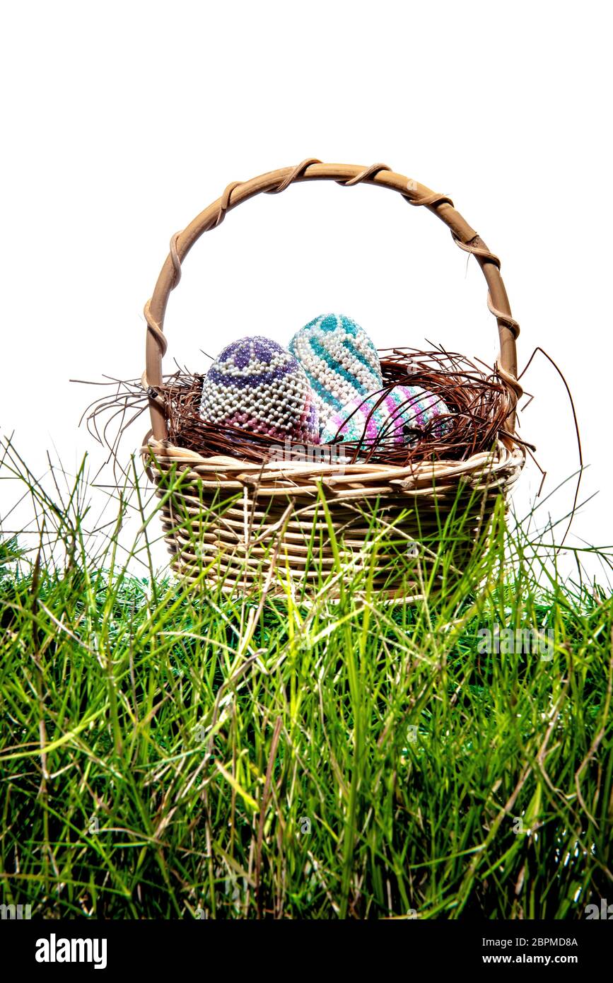 Colorate le uova di pasqua nel nido sul cestello in legno a erba verde su sfondo bianco. Buona Pasqua Foto Stock