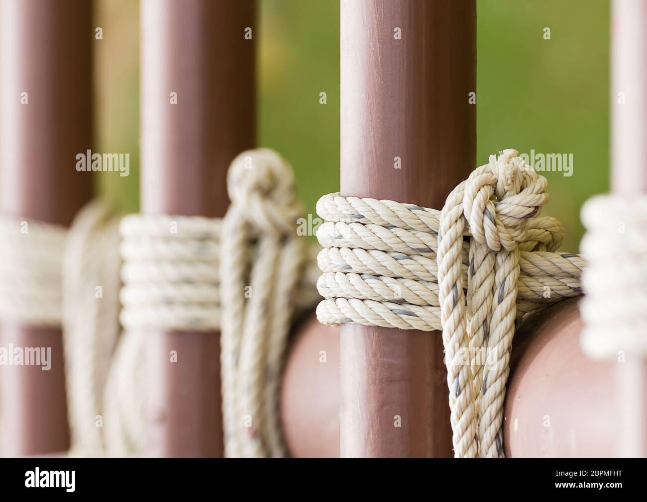 Chiusura del nodo di corda attorno ad una recinzione metallica, corda allacciate knot tubo metallico pole Foto Stock