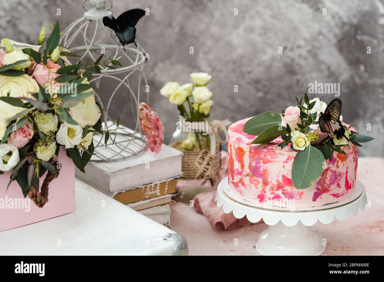 Torta rosa decorata con fiori e farfalle reali rosa atmosfera romantica Foto Stock