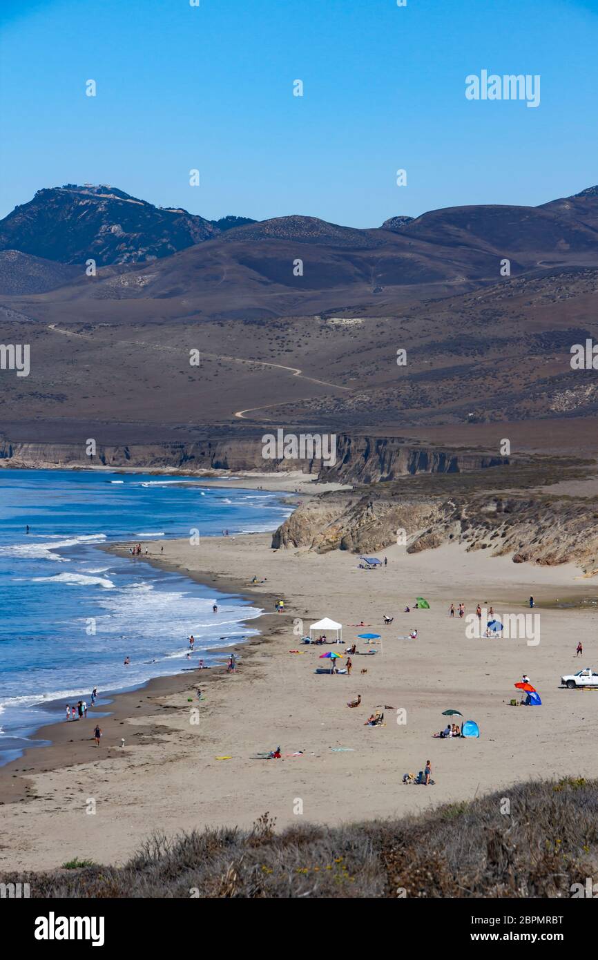 Persone su una spiaggia soleggiata di una baia nascosta Foto Stock