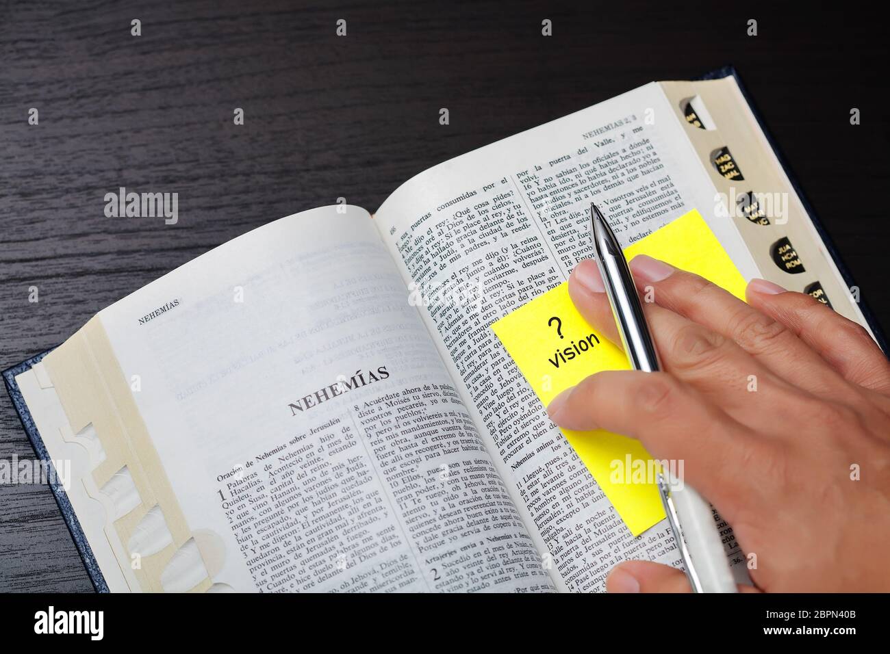 Una persona che studia la sua fede con una domanda o un dubbio sulla visione del profeta Nehemias, usando una bibbia Santa tradotta spagnola. Foto Stock