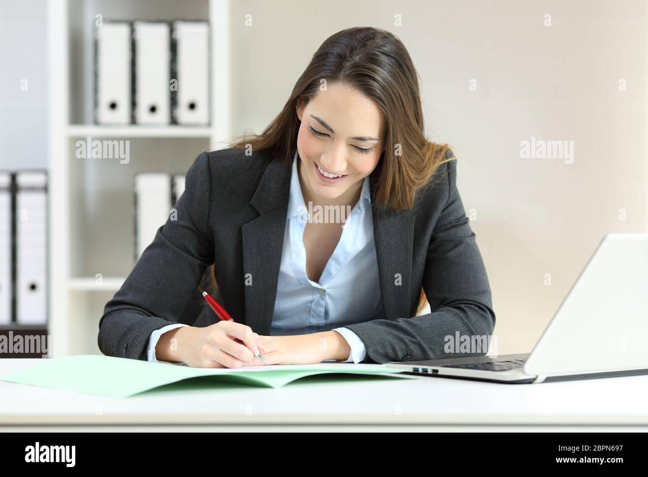 Vista anteriore verticale di un esecutivo di firmare un documento su una scrivania in ufficio Foto Stock