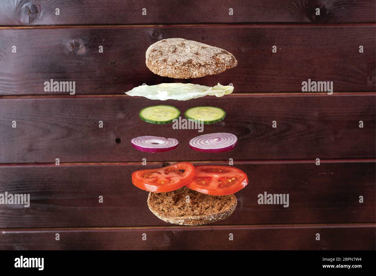 Primo piano vista su un panino fatto in casa con ingredienti volanti su sfondo di legno. Foto Stock