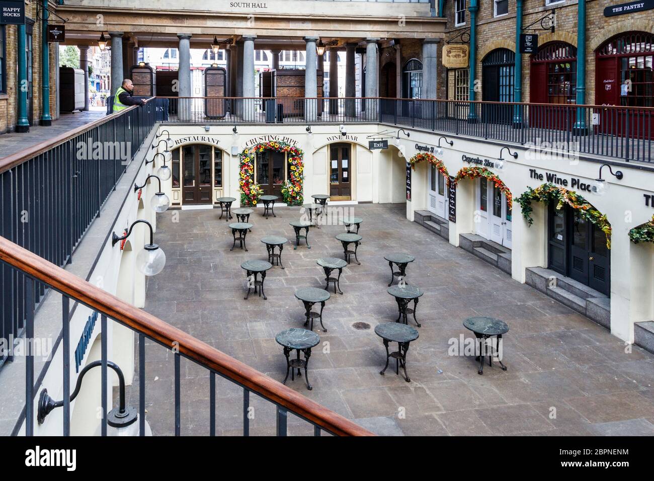 Una guardia di sicurezza guarda giù ai negozi e ristoranti chiusi nel mercato di Covent Garden durante un fine settimana durante il blocco pandemico del coronavirus, Londra, Regno Unito Foto Stock