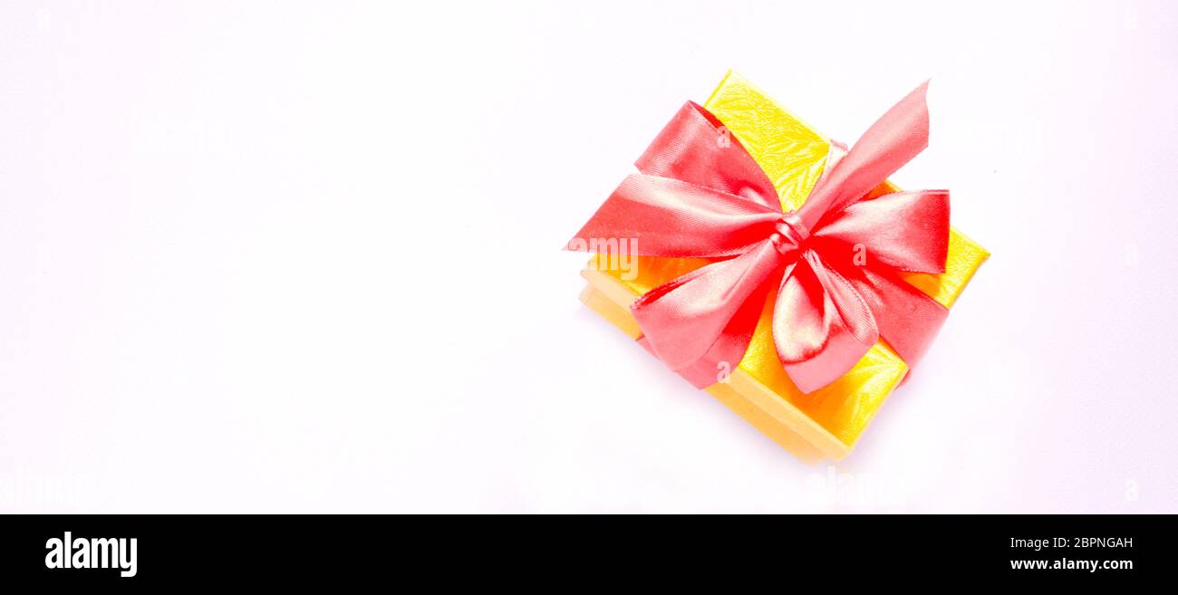 Confezione regalo con arco rosso su sfondo rosa. Disposizione piatta Foto Stock