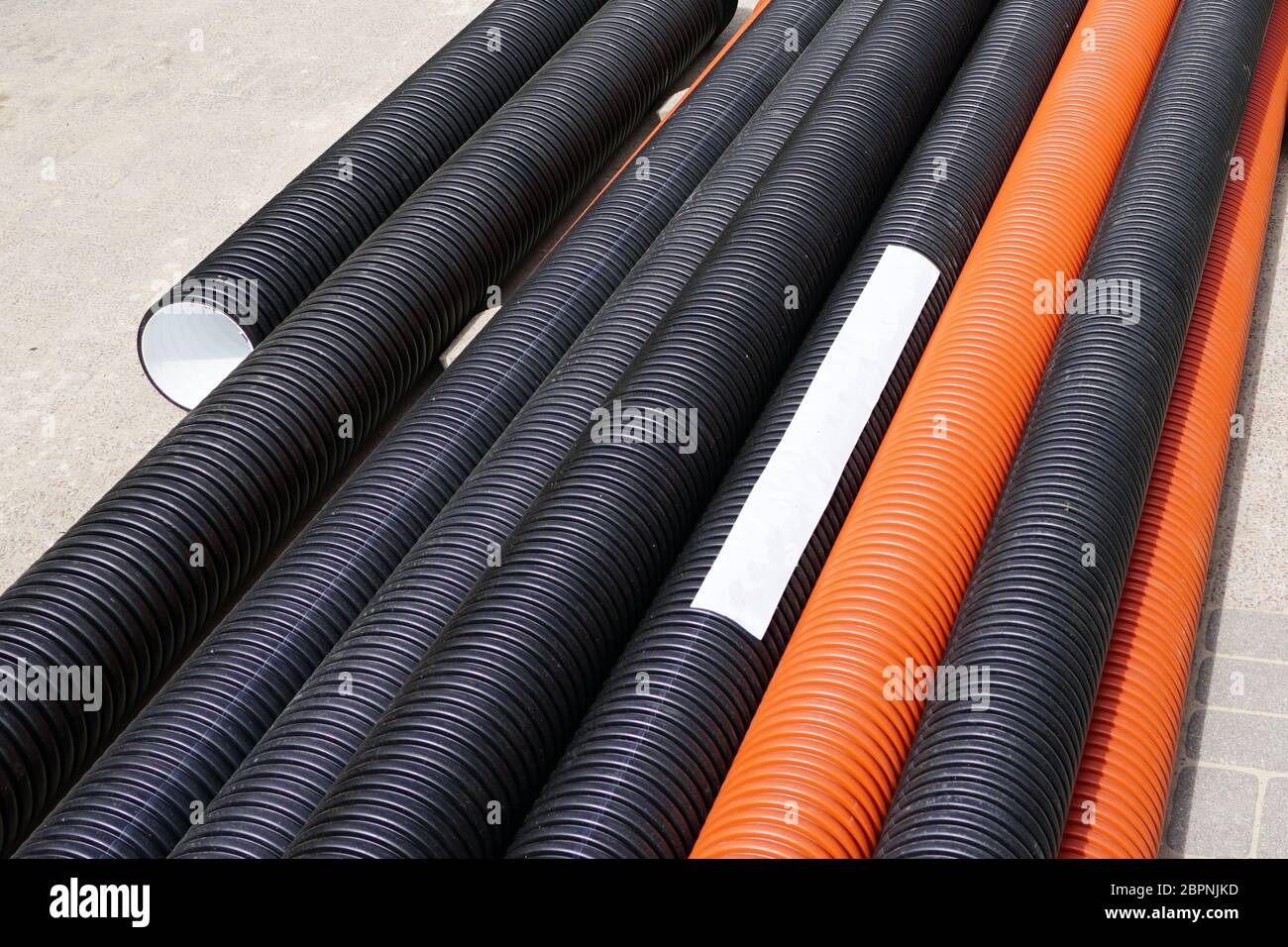 nuovi tubi in plastica arancione e nero sul cantiere Foto Stock
