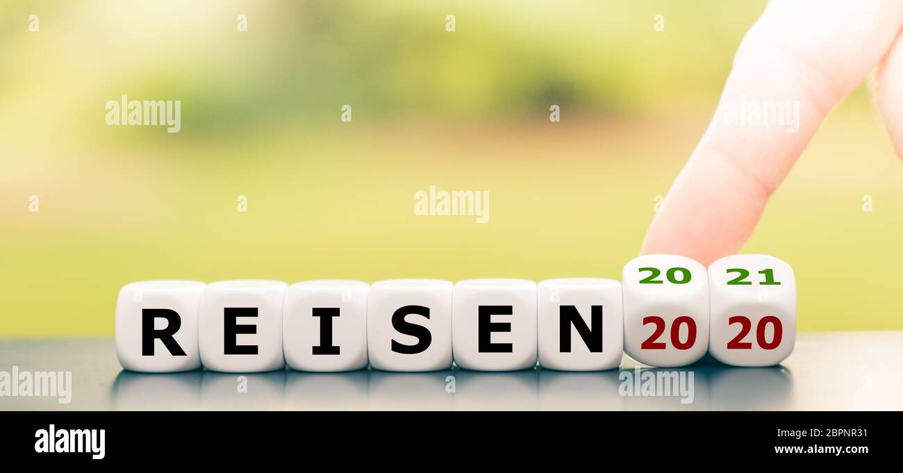 Nessun viaggio nel 2020 a causa del virus corona. La mano gira i dadi e cambia l'espressione tedesca "Reisen 2020" ("Travel 2020") in "Reisen 2021" ("strada Foto Stock