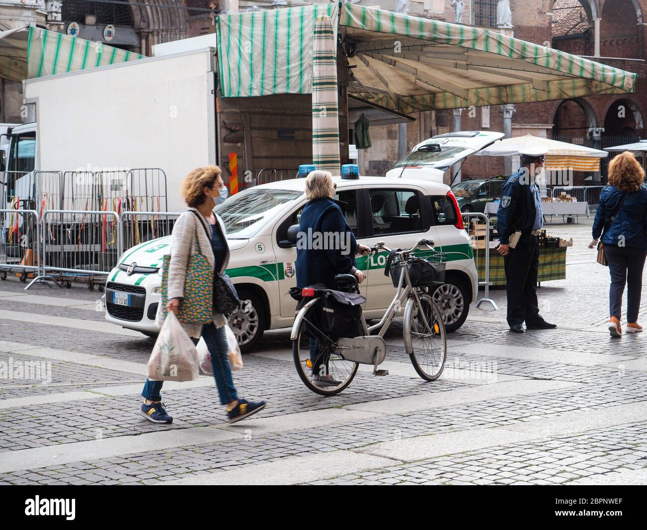 Cremona, Lombardia, Italia - Maggio 2020 persone locali che indossano maschera facciale protettiva in linea e controlli più severi della polizia all'accesso al mercato stradale Foto Stock