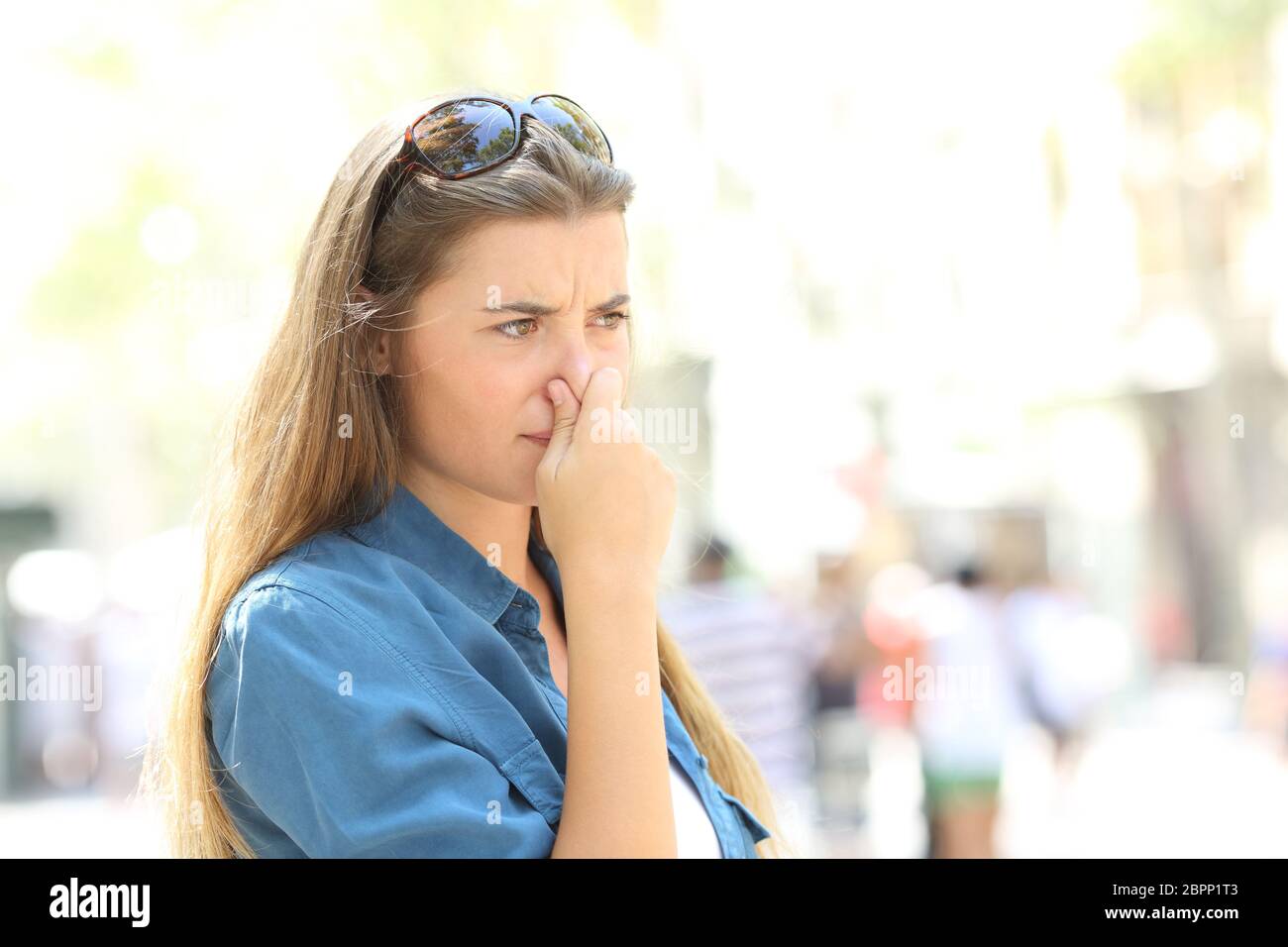 Ragazza che coprono il suo naso a causa di cattivo odore in strada Foto Stock