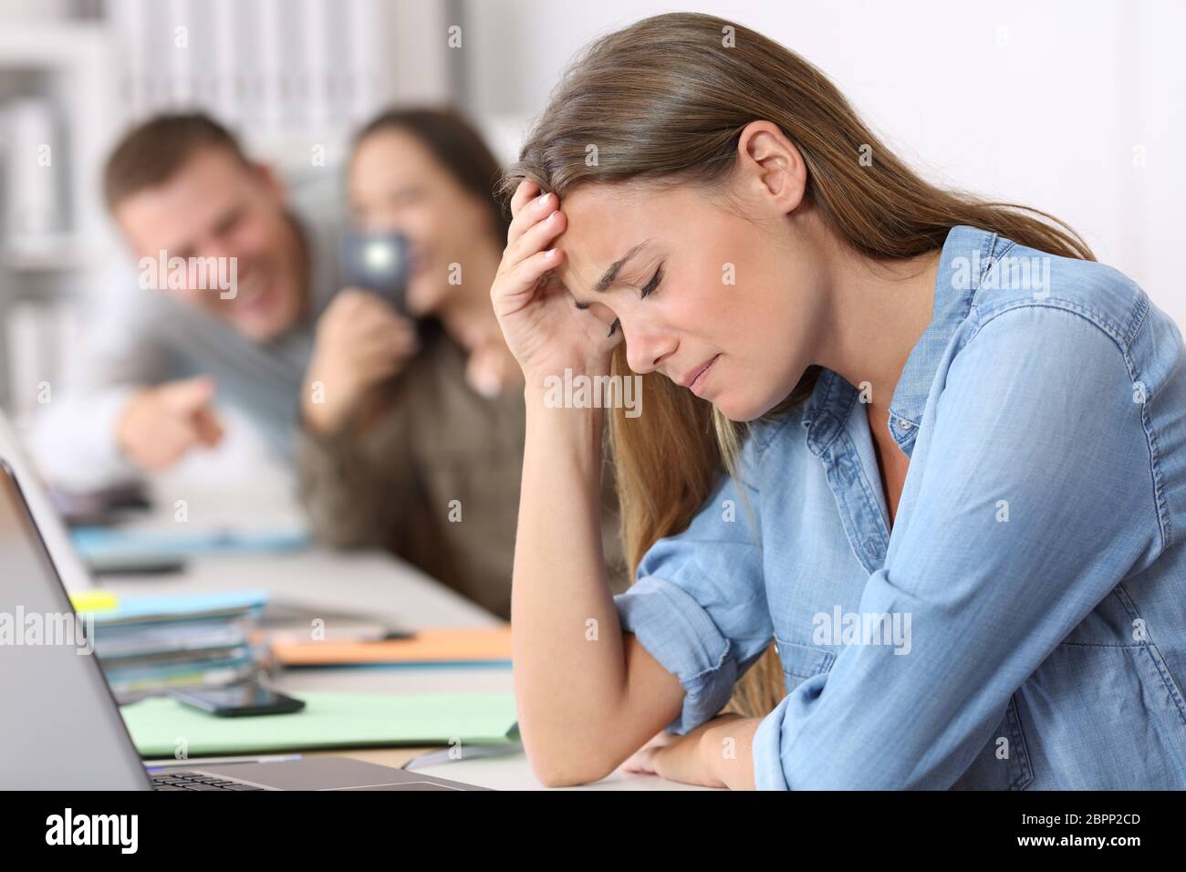 Triste cyber bullismo vittima di essere fotografati dai suoi colleghi in ufficio Foto Stock