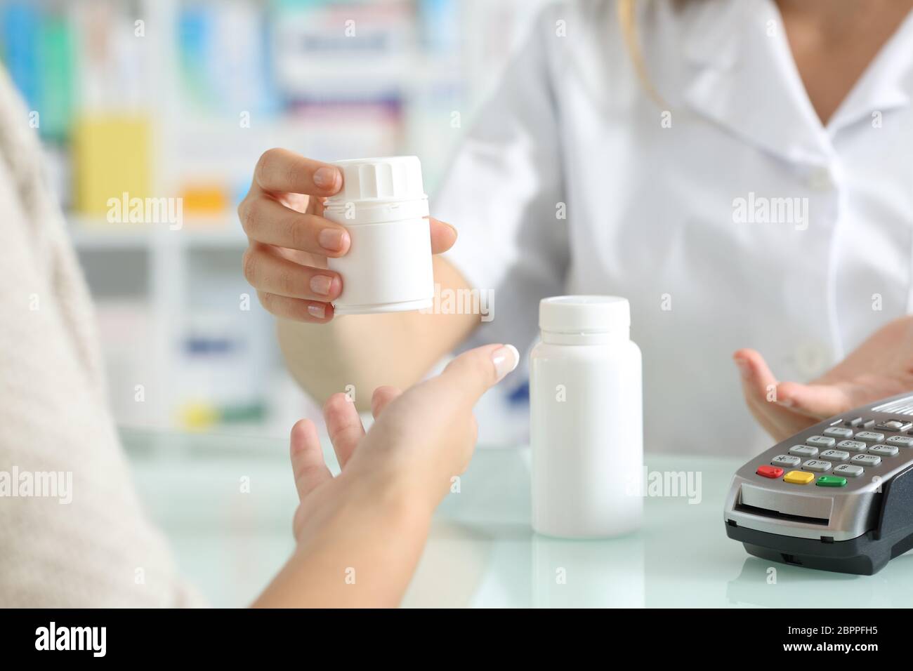 Primo piano di un farmacista che vende farmaci a un cliente su un banco di farmacia Foto Stock