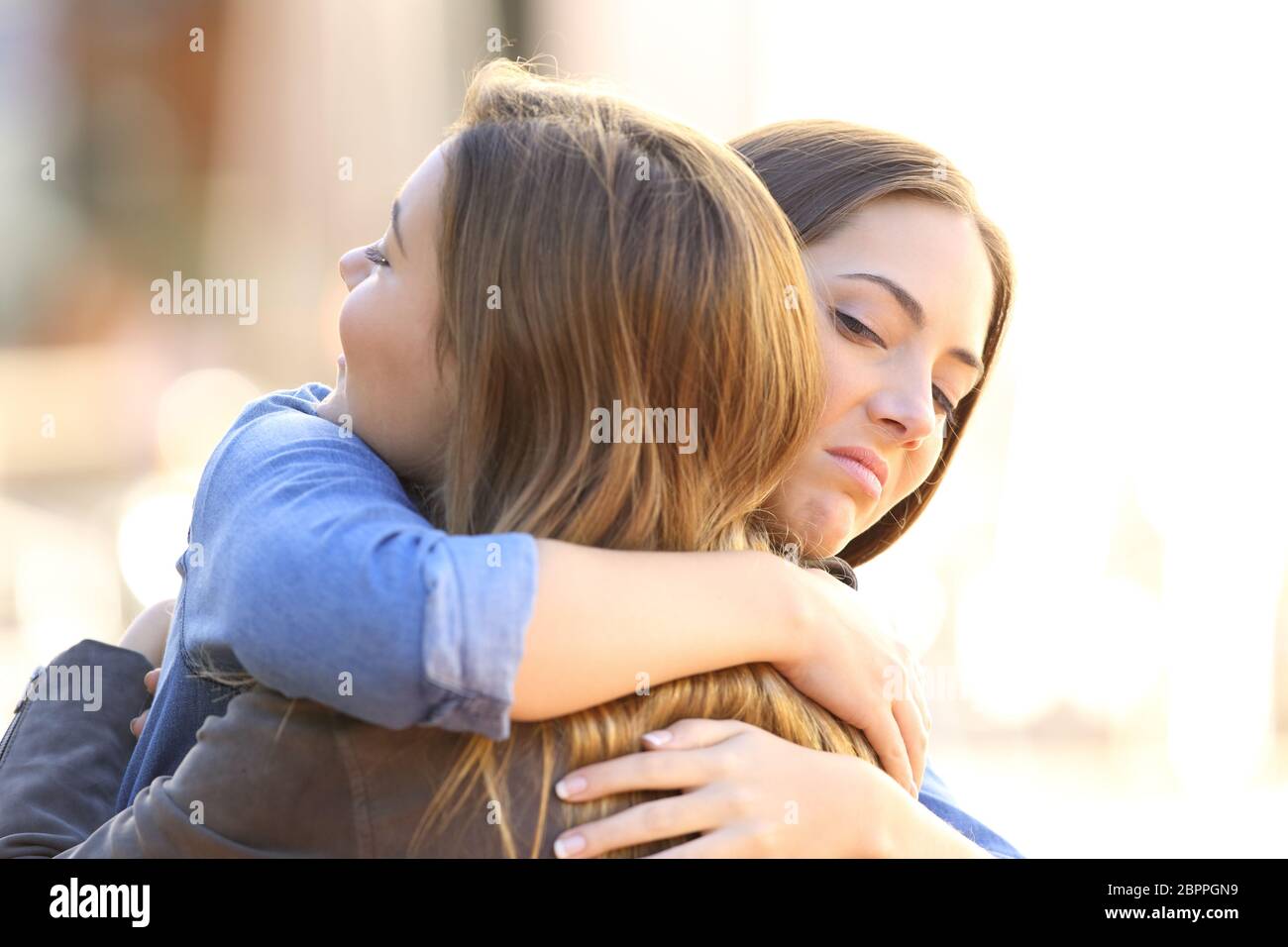 Ragazza ipocrita abbracciando un amico all'aperto in strada Foto Stock