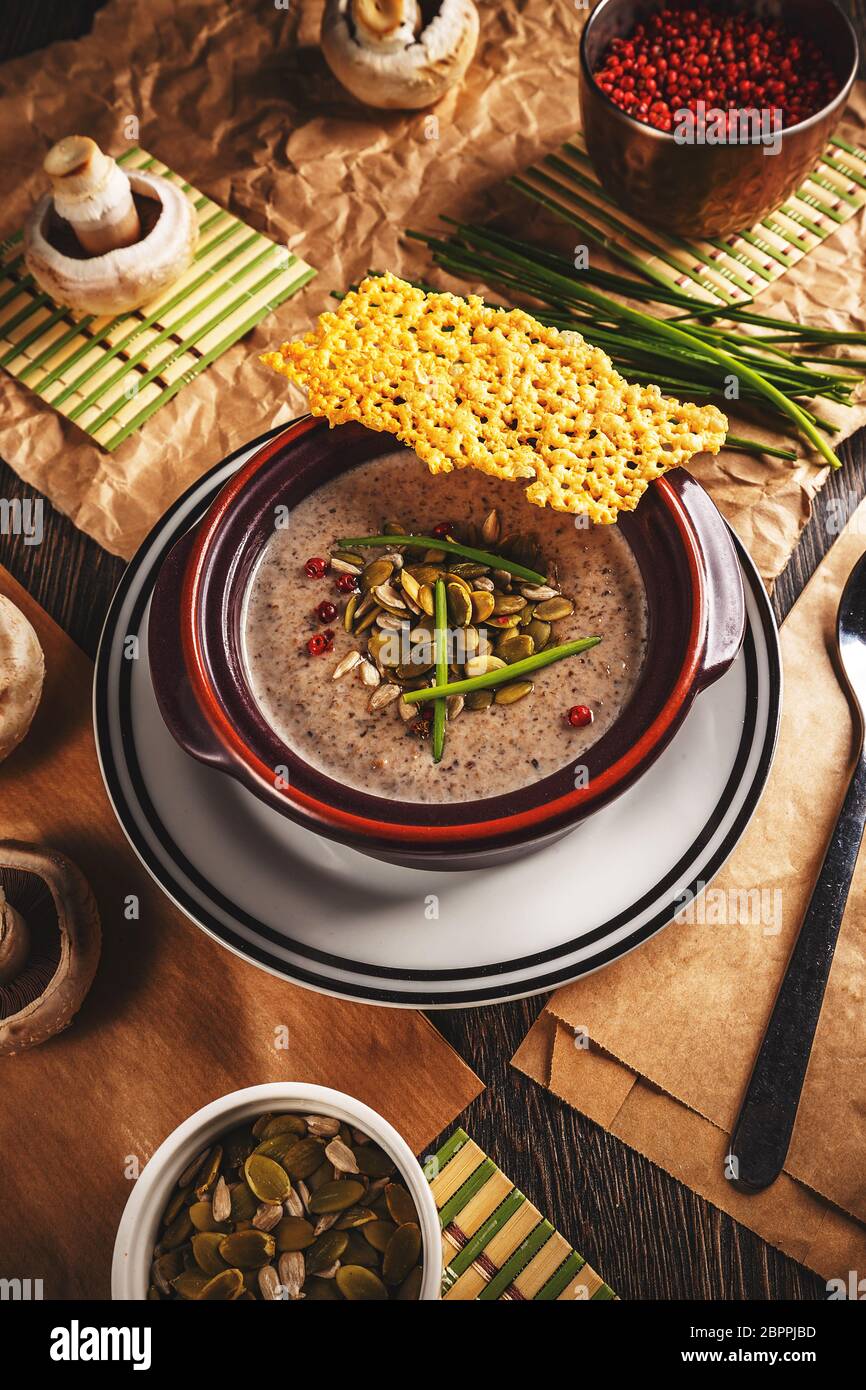 Ciotola di deliziosa crema di zuppa di funghi servita con i semi di zucca e croccante di formaggio Foto Stock