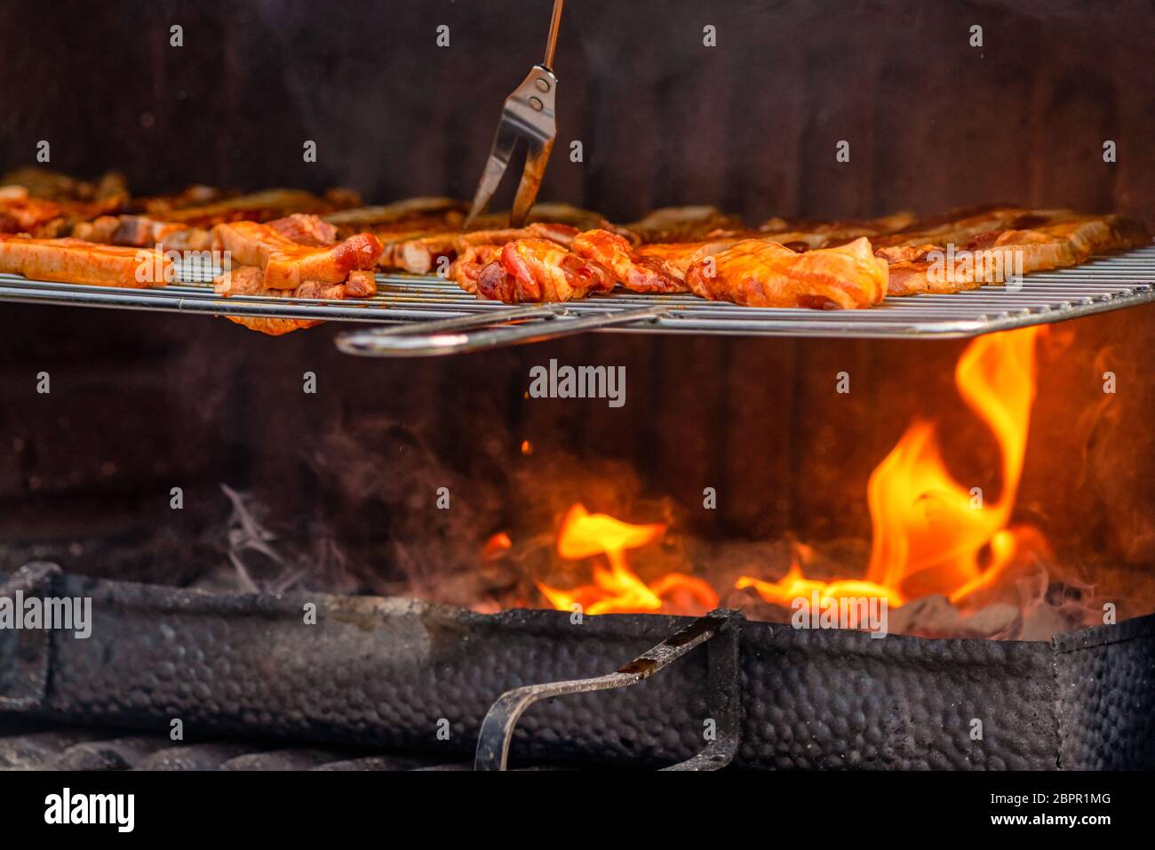 La carne alla griglia è appena finita su una fiamma calda in un barbecue da vicino. Foto Stock