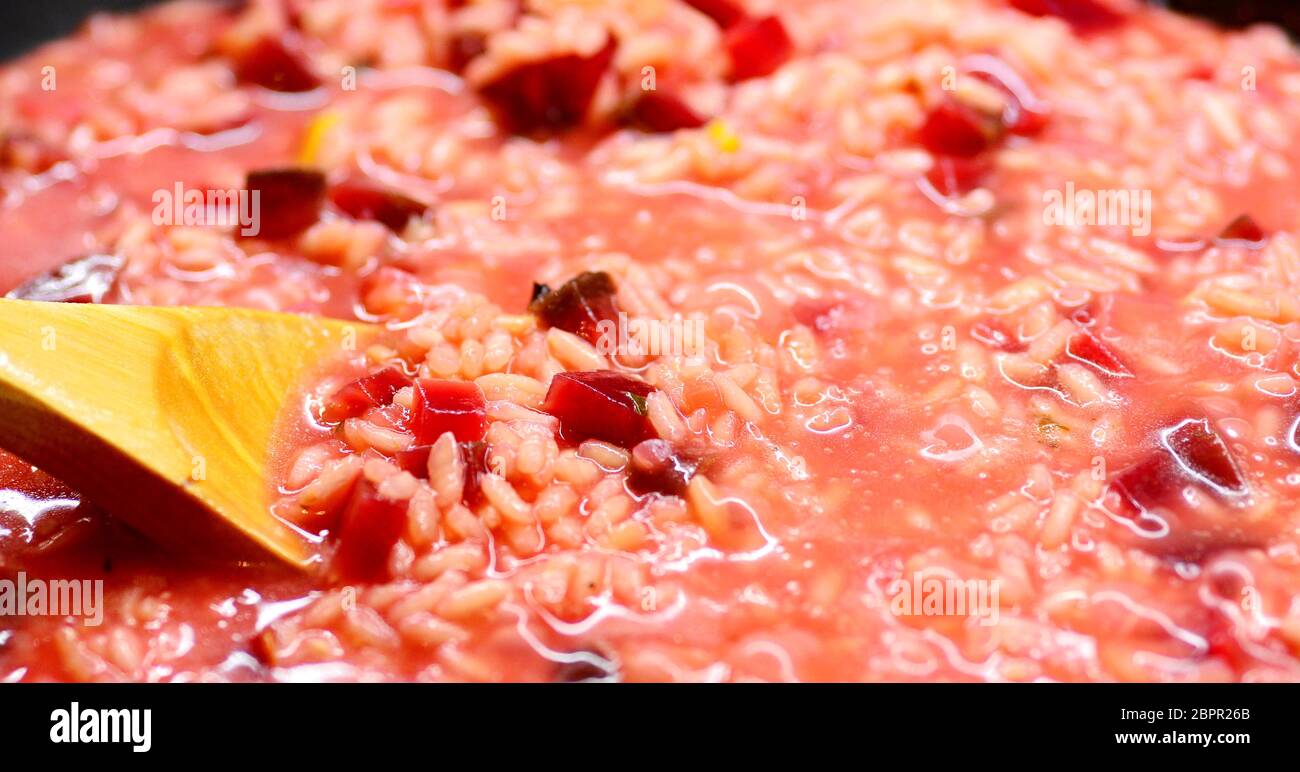 Close-up di un Italiano cremoso Risotto di barbabietole e agitando il cucchiaio di legno. Foto Stock
