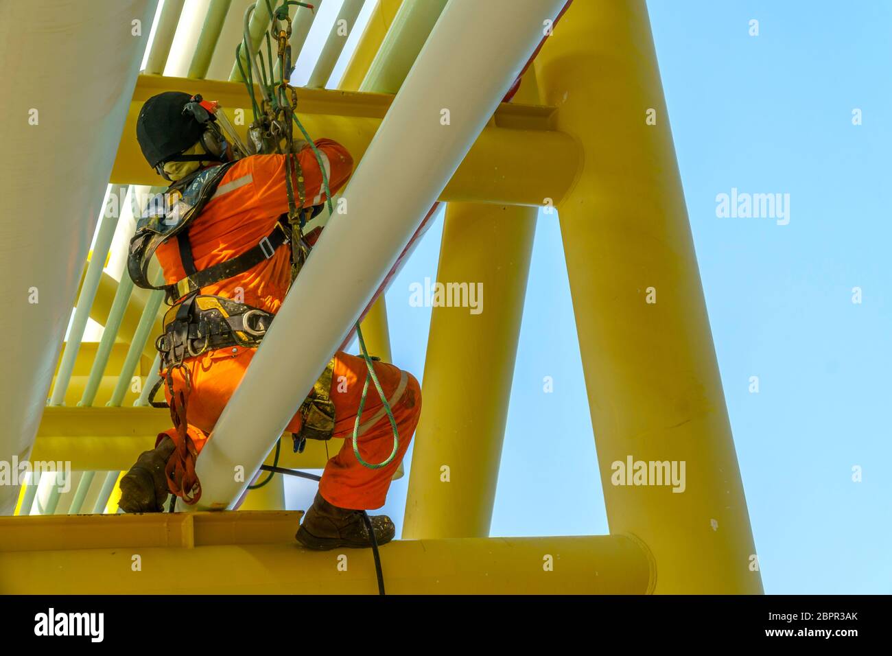 Lavoro in altezza. Una discesa dalla parte posteriore con tuta sporca che indossa dispositivi di protezione individuale (PPE) appesi alle linee di vita seduti sulla pipelina Foto Stock