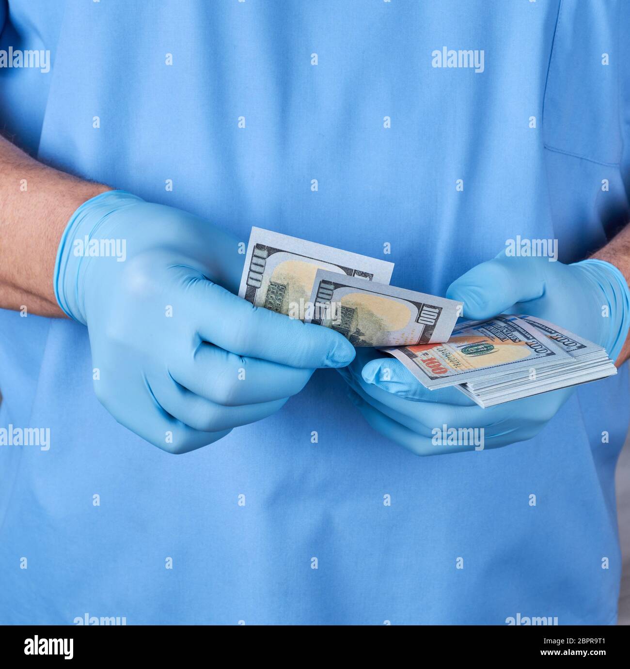 Dottore in uniforme blu e guanti racconta il denaro, il concetto di dare prendere per servizi medici Foto Stock