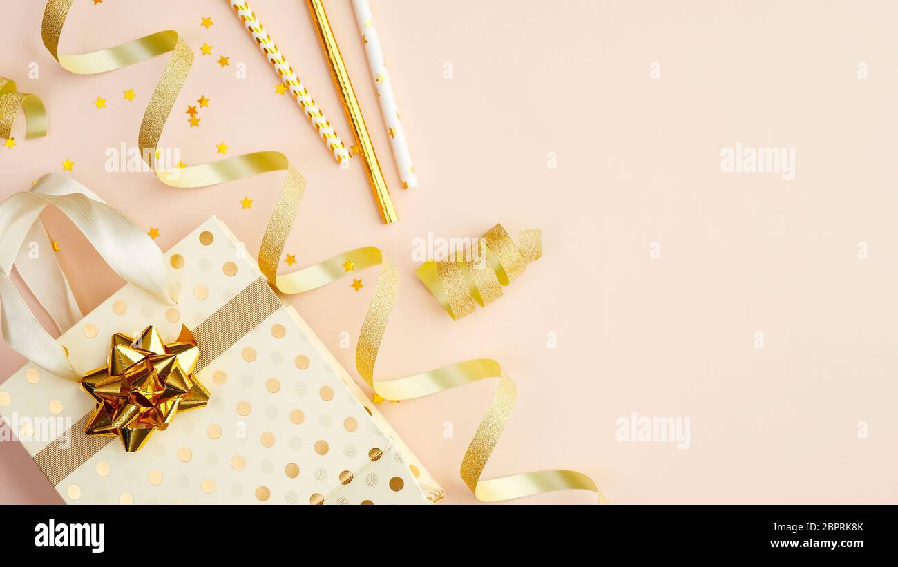 Borsa con regali, streamer party e stelle di confetti d'oro su tavolo beige. Concetto di festa di compleanno, Natale o anniversario. Posa piatta, Foto Stock